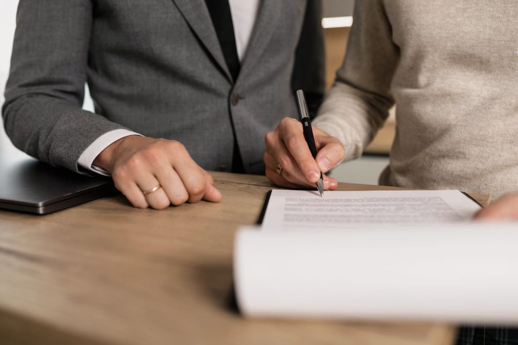 Mastering the First Impression: Your intriguing post title goes here Close-up of businessmen signing documents at a wooden table in an office.