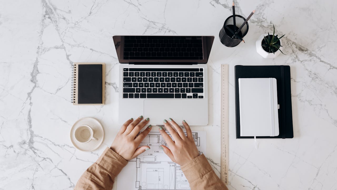 Crafting Captivating Headlines: Your awesome post title goes here Top view of a stylish home office desk with a laptop, planner, and coffee cup, showing hands on a blueprint.
