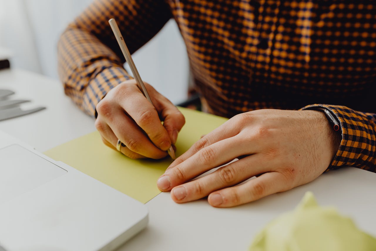 Home Close-up of a person writing on yellow paper, displaying clear handwriting and attention to detail.